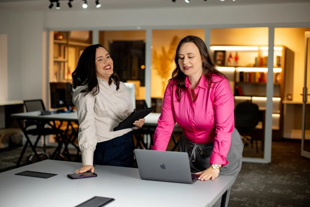 As duas instrutoras trabalhando juntas, com um tablet e um notebook